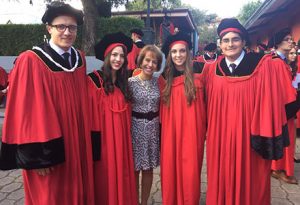 Chancellor Folt with 4 Universidad San Francisco de Quito graduates. Their cap and gowns are red with black detailing.