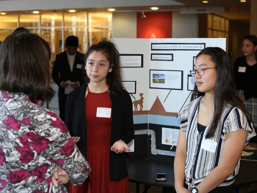 Two students share poster with visitor