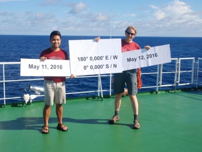John Paul Balmonte ’17 Ph.D. with another student on boat holding up sign with equator coordinates