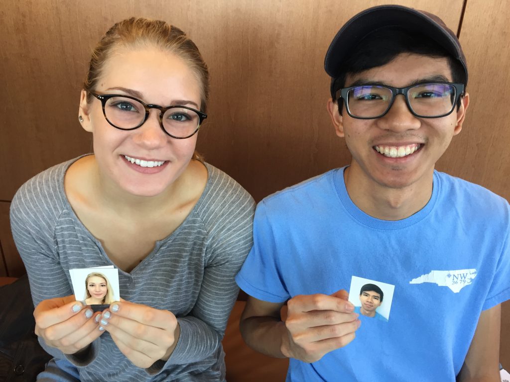 Photo of two students holding their passport photos