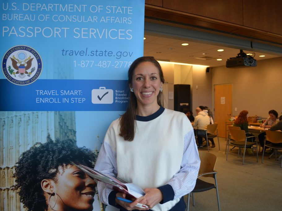 Passport renewal participant standing in front of a sign
