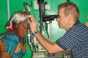 A man is using a optometry device to examine a patient's eyes.
