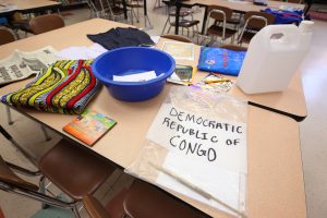 Items from a culture kit for the Democratic Republic of the Congo are spread on a classroom table.