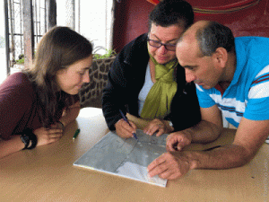 Three people look over map.