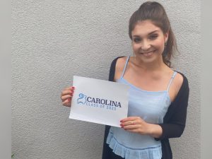 Katharina Malena Krause smiling and holding a sign that says "Carolina Class of 2023"
