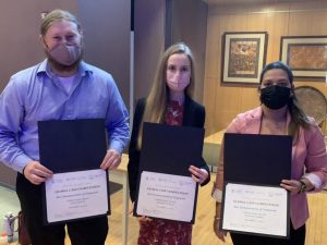 Three students holding certificates. All students are wearing face masks.
