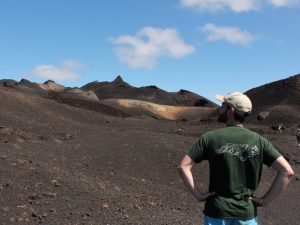 Will looking out at the volcano on Isabela Island while wearing a t-shirt showing a geologic map of NC.