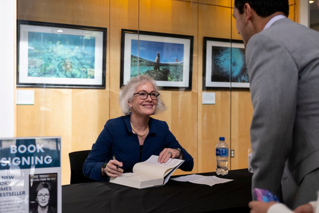 Marie Yovanovitch smiling to a person as she signs their copy of her book.