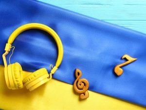 yellow headphones and figures of musical notes resting on top of a Ukraine flag.