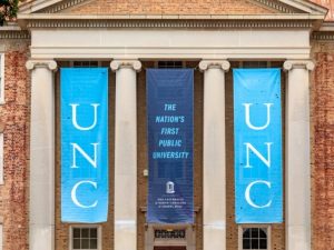 Banners hanging from South Building with text "UNC" and "The nation's first public university"