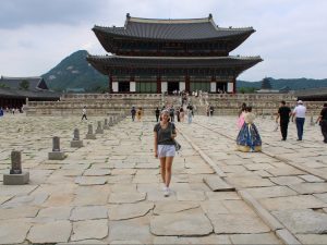 Girl standing in front of a former royal palace. Korean-style architecture.