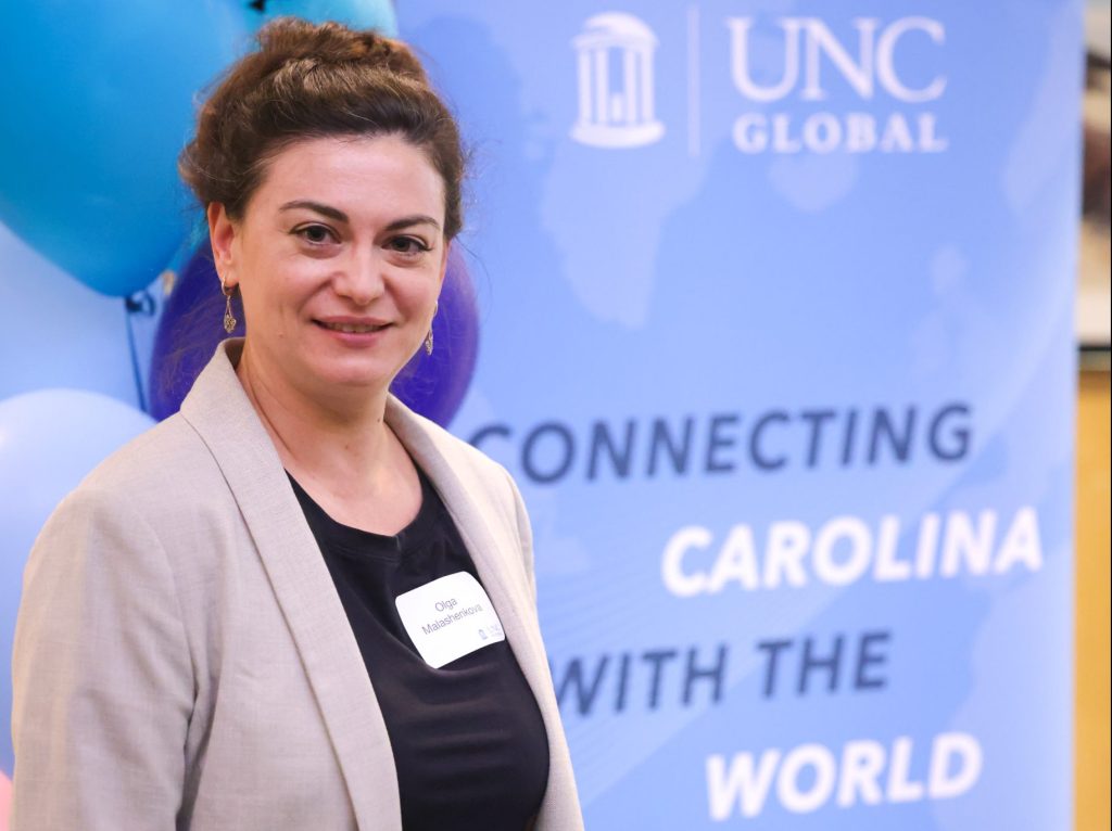 Olga stands next to a banner that says "UNC Global: Connecting Carolina with the World"