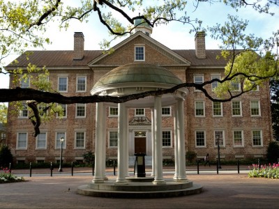 The Old Well framed by tree branches. In the background, South Building, where the Chancellor's office is located.