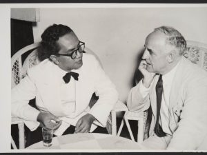 Black and white photo. Two men talking to each other.