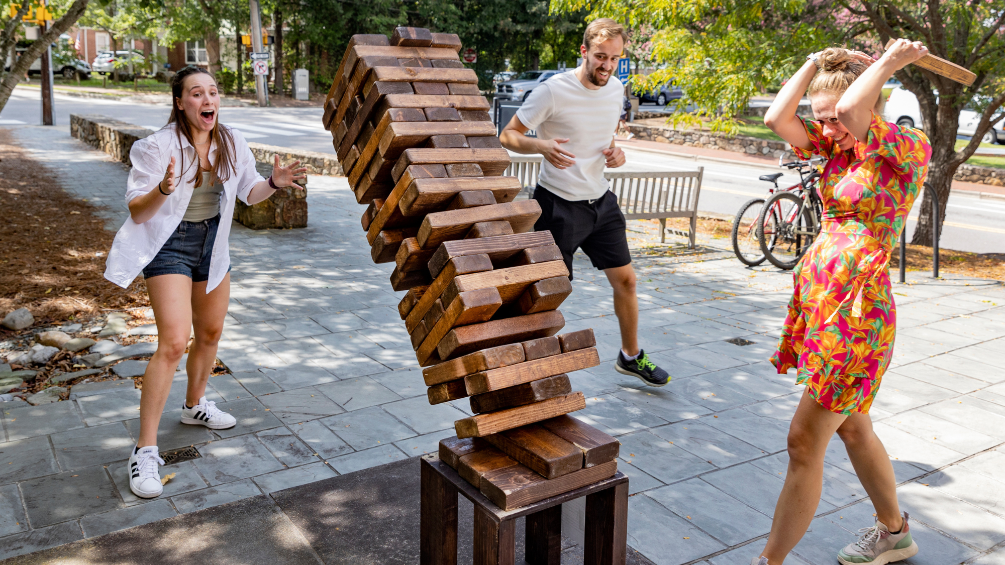 Tall Jenga stack tumbles to the ground. The people playing look excited and happy.